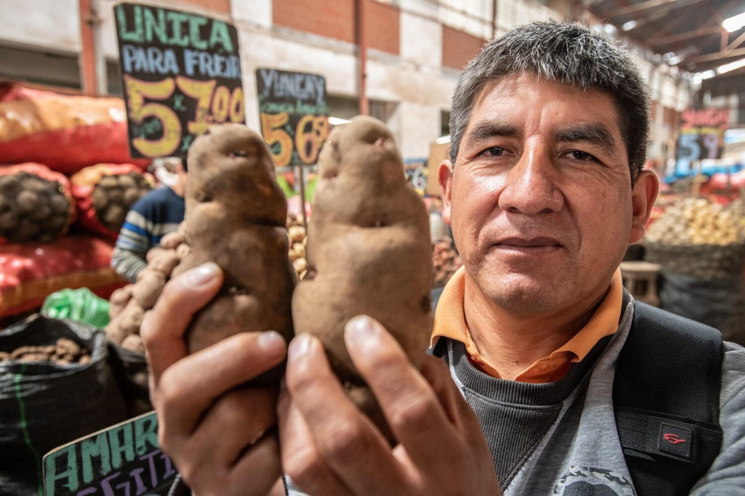 Man holding potatoes at a market. 